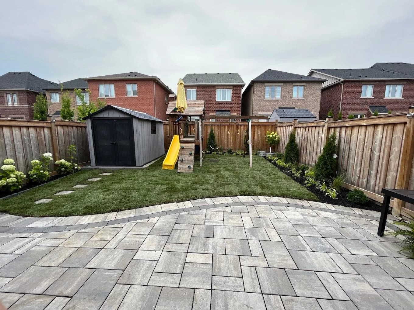 Curved paver patio overlooking a newly sodded family backyard