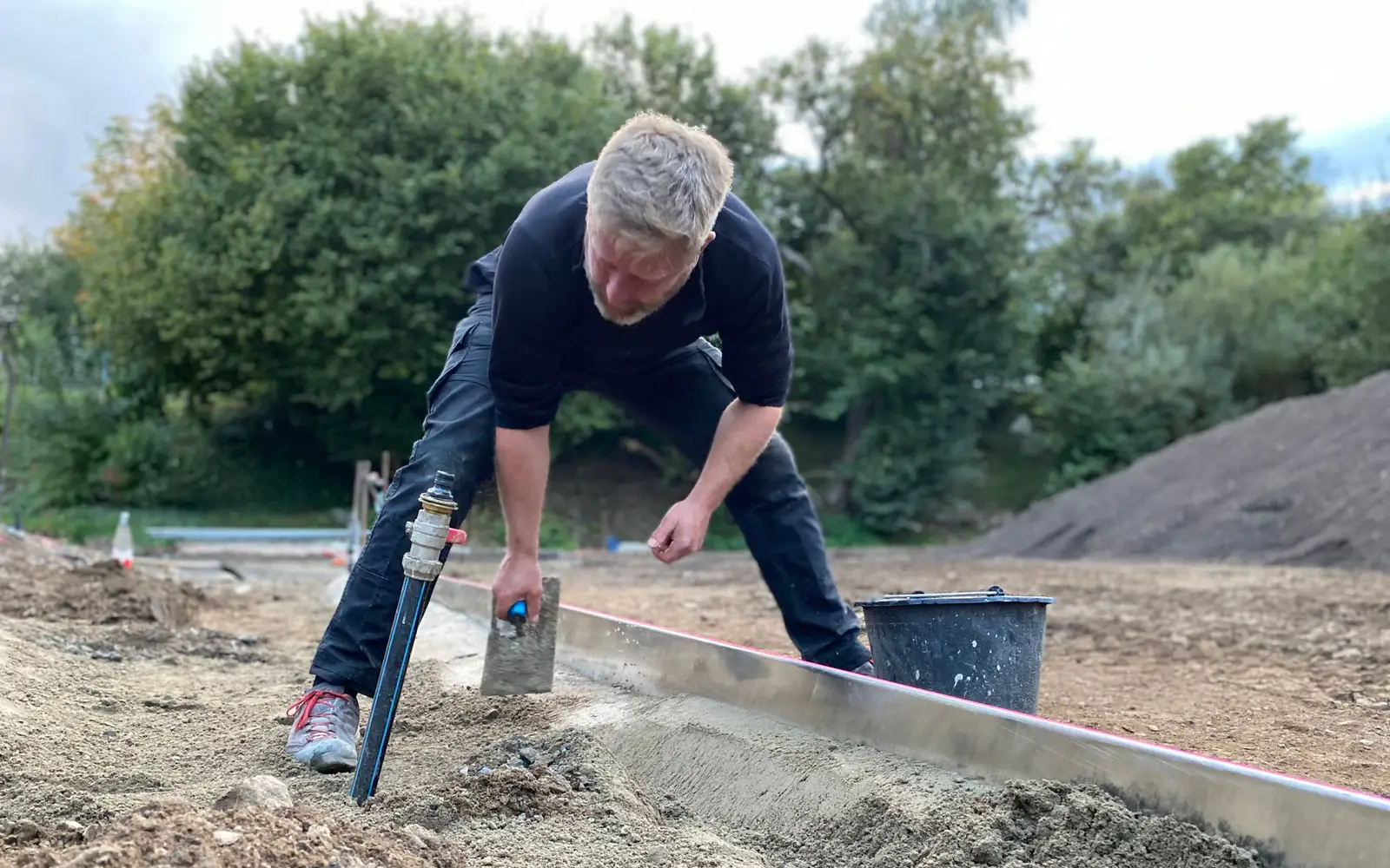 A tradesperson setting levels over a prepared landscape base