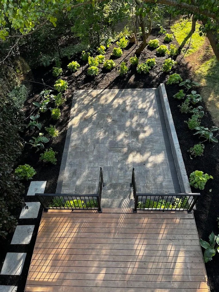 Elevated deck overlooking a shaded paver garden terrace
