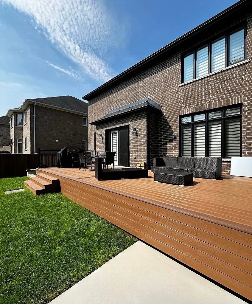 Broad composite deck extending across a brick home