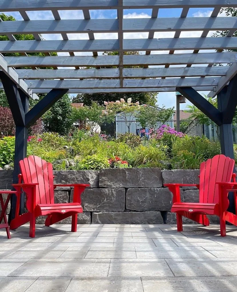 Pergola seating area backed by a natural stone retaining wall and flowers