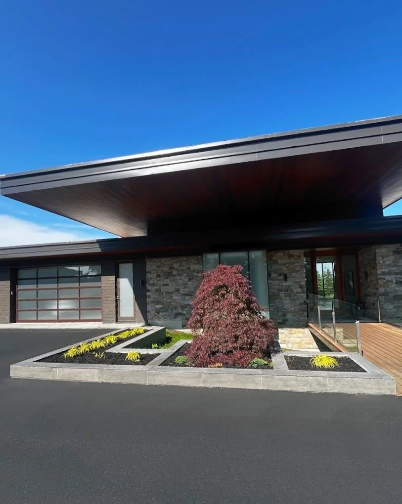 Modern home entrance framed by geometric planters and a specimen tree