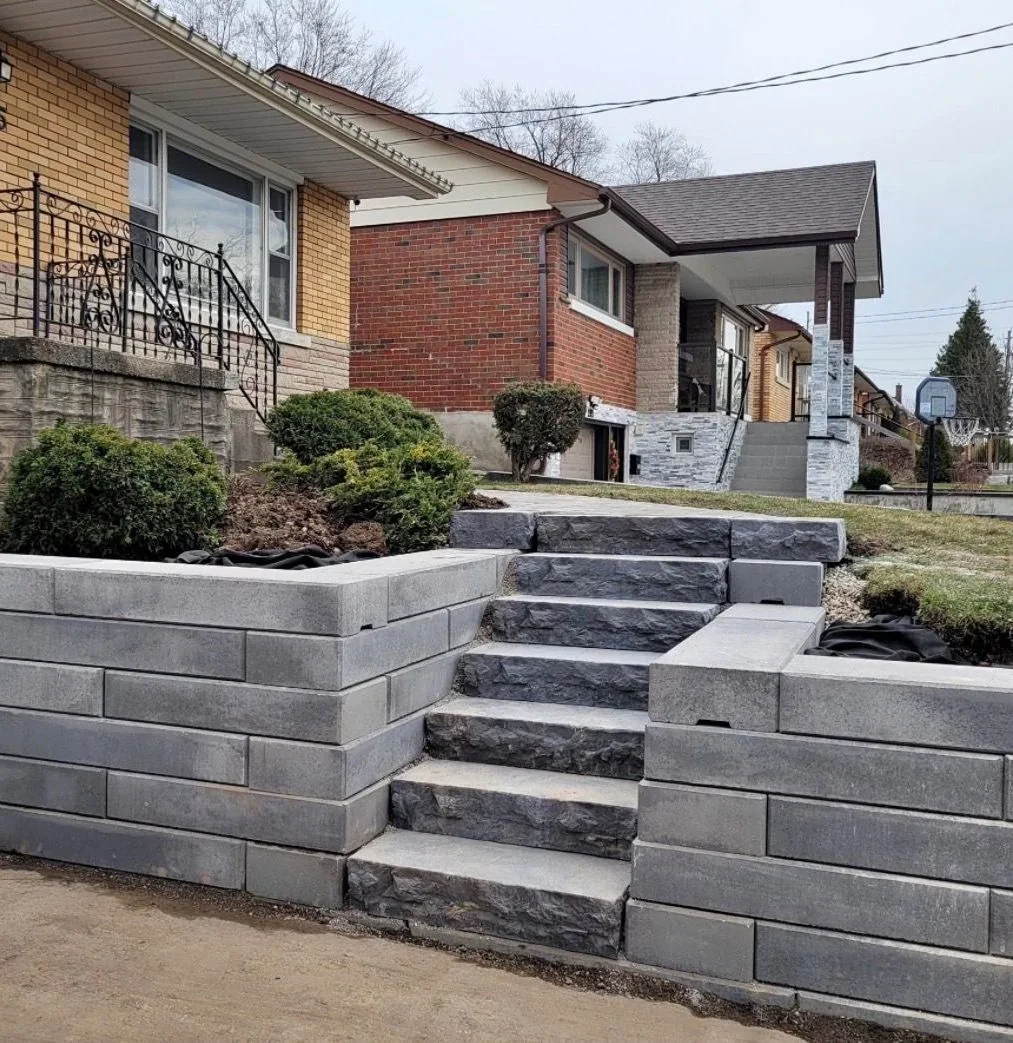 Tiered retaining wall and natural stone steps reshaping a sloped front yard