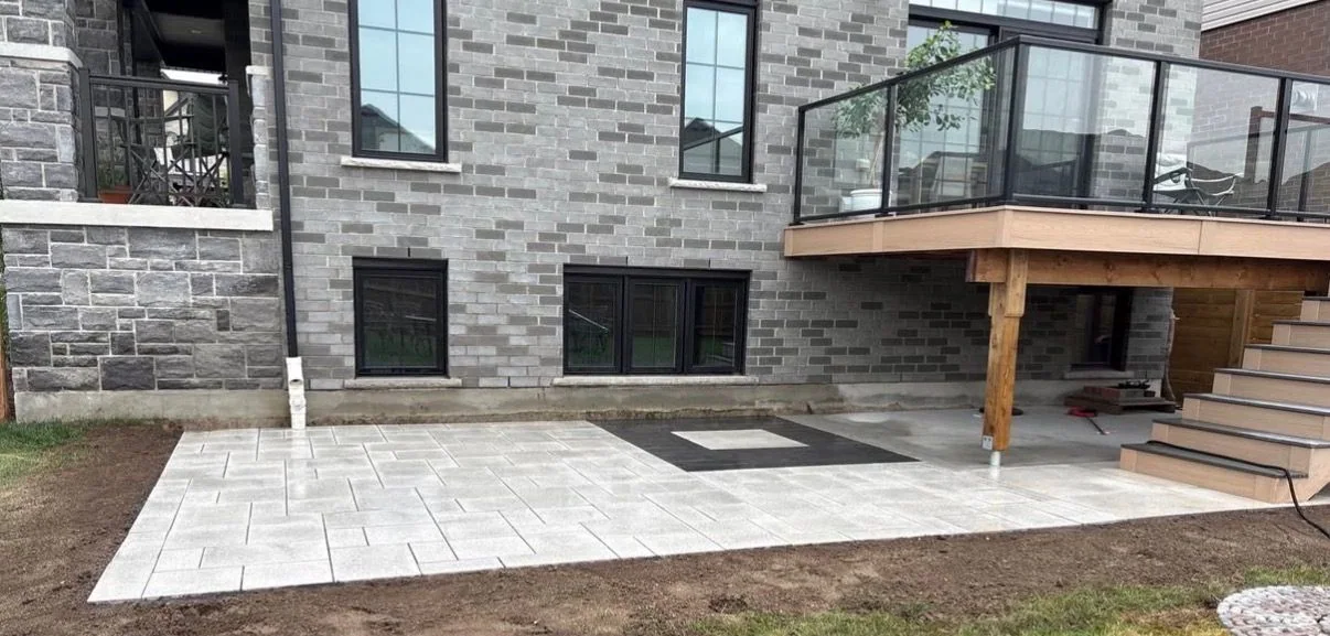 New backyard patio beneath a raised deck during site completion
