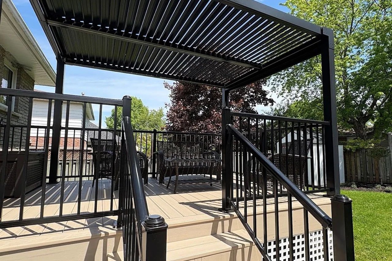 Raised deck and black louvered pergola surrounded by lawn