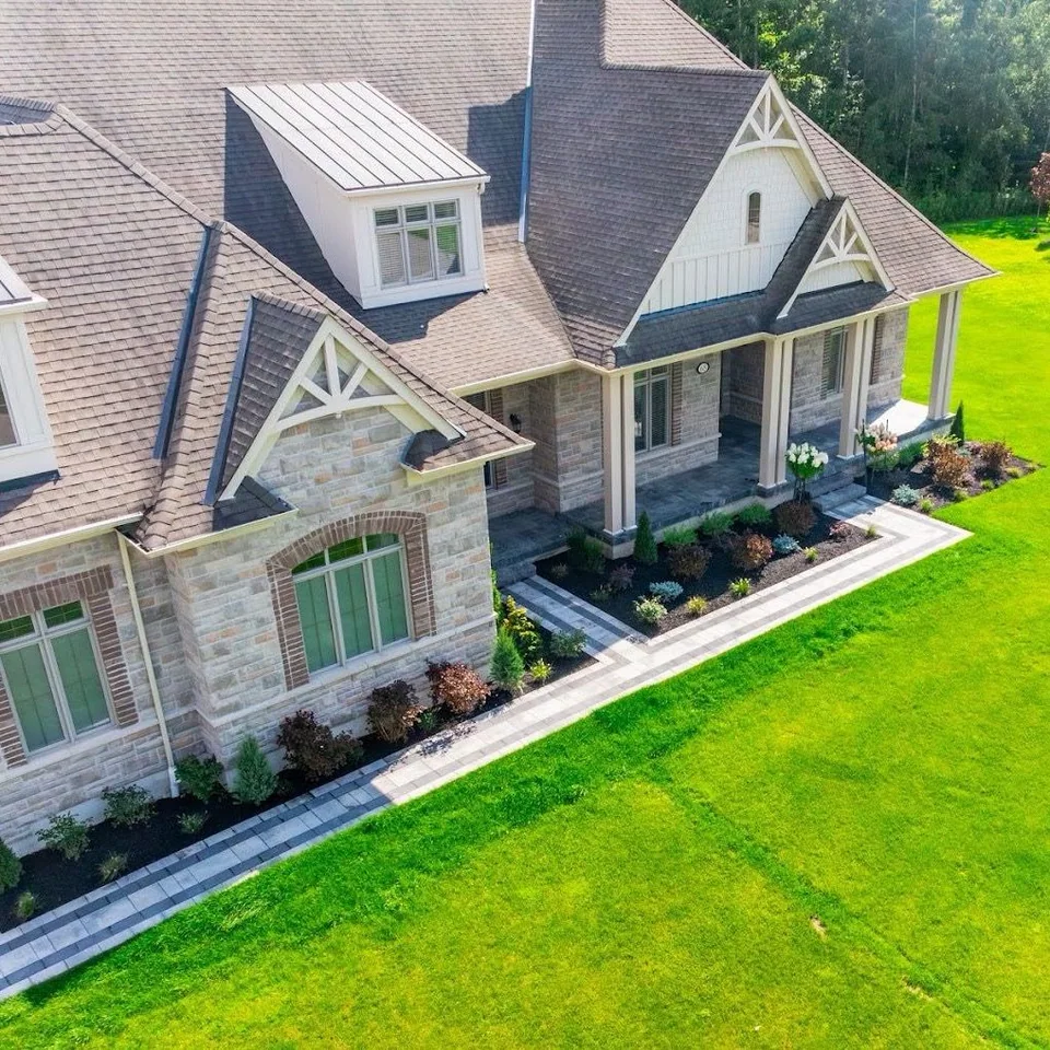 Aerial view of a large home with formal foundation planting and expansive lawn