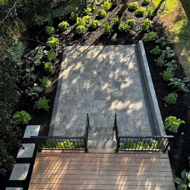 Elevated deck overlooking a shaded paver garden terrace