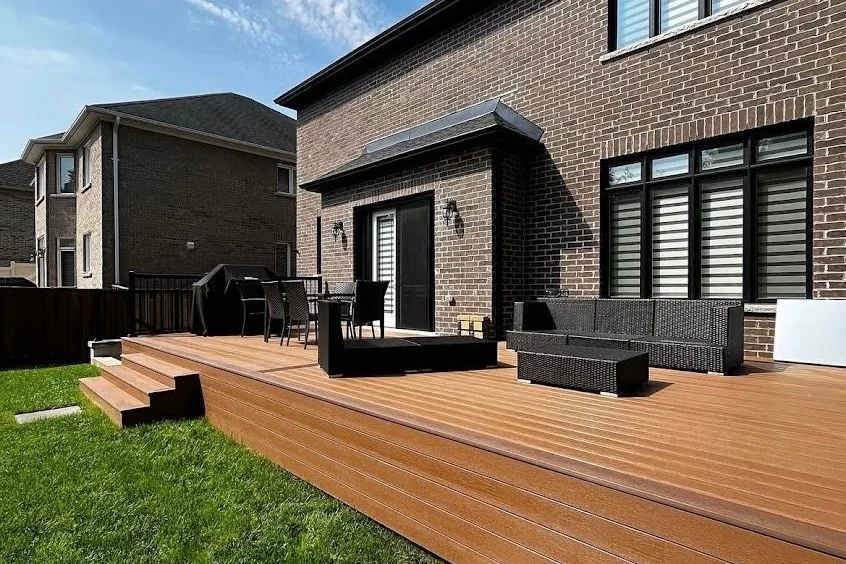 Broad composite deck extending across a brick home
