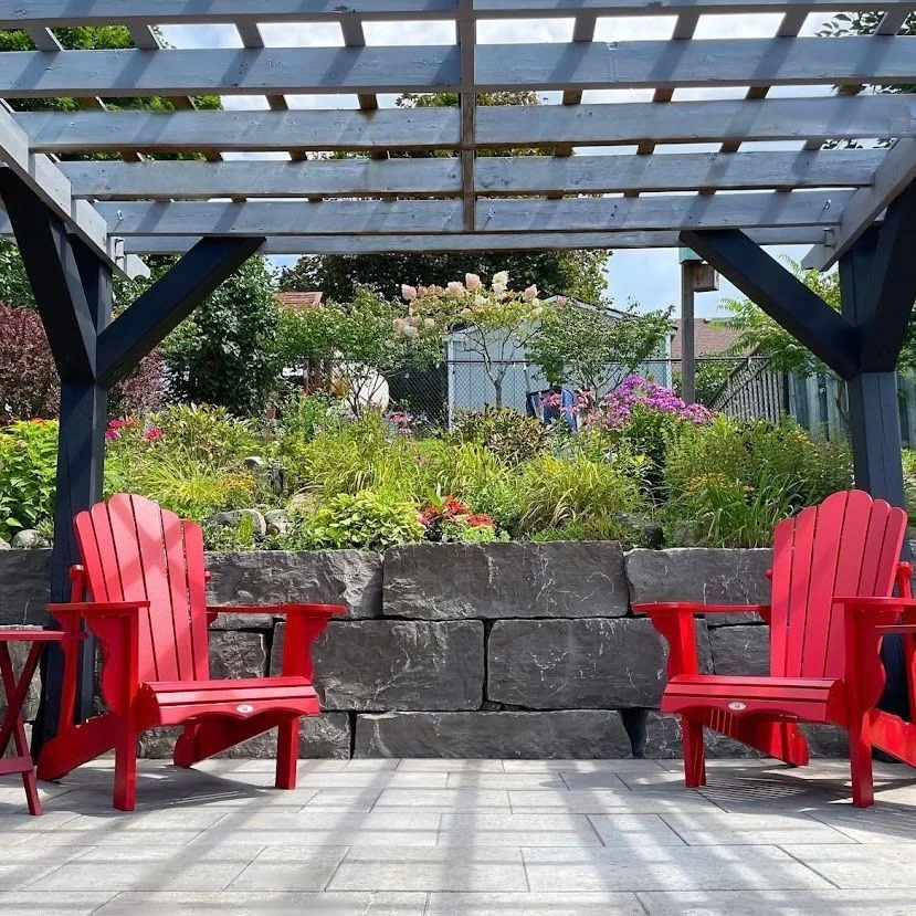 Pergola seating area backed by a natural stone retaining wall and flowers