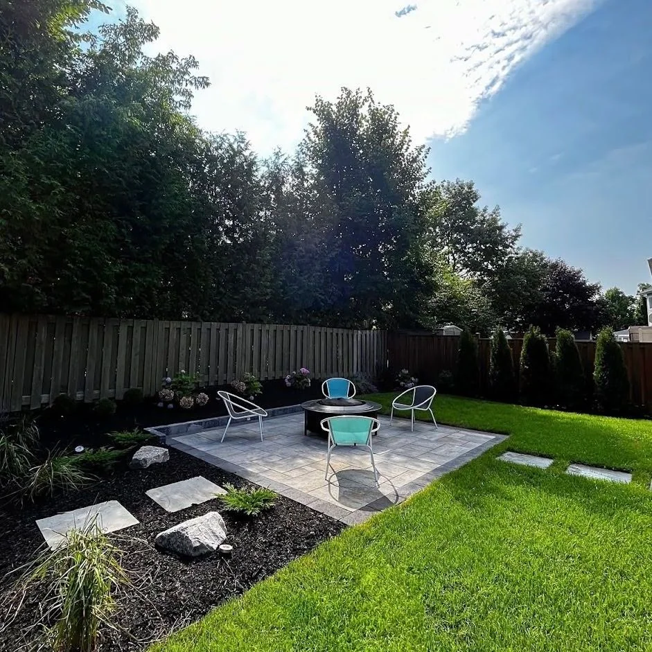 Compact backyard patio with a fire table, lawn, and dark planting beds