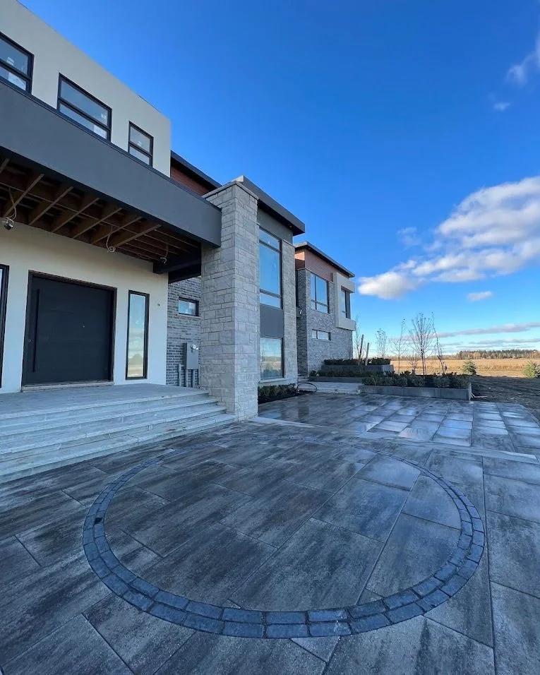 Large-format paver terrace with a circular border beside a contemporary home