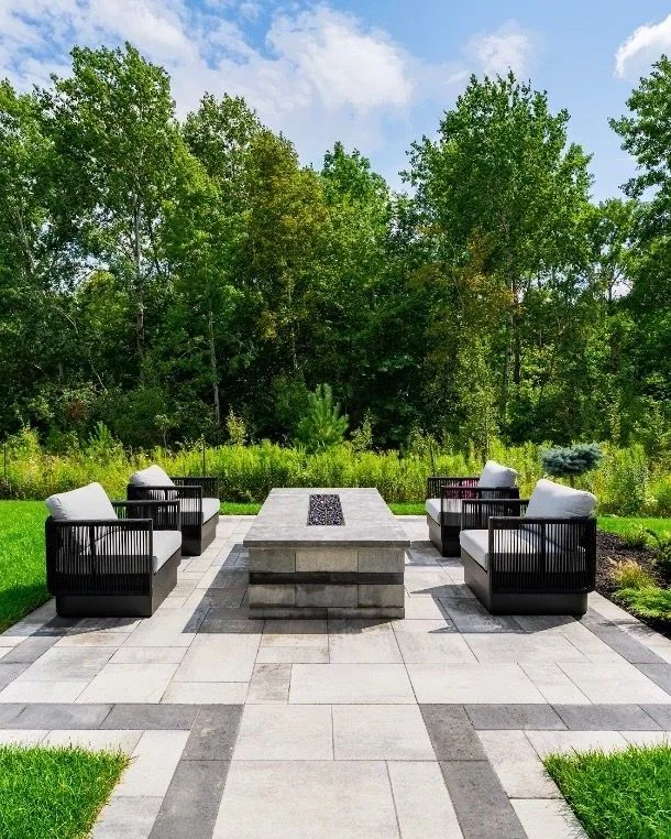 Symmetrical fire-table terrace framed by lawn and woodland