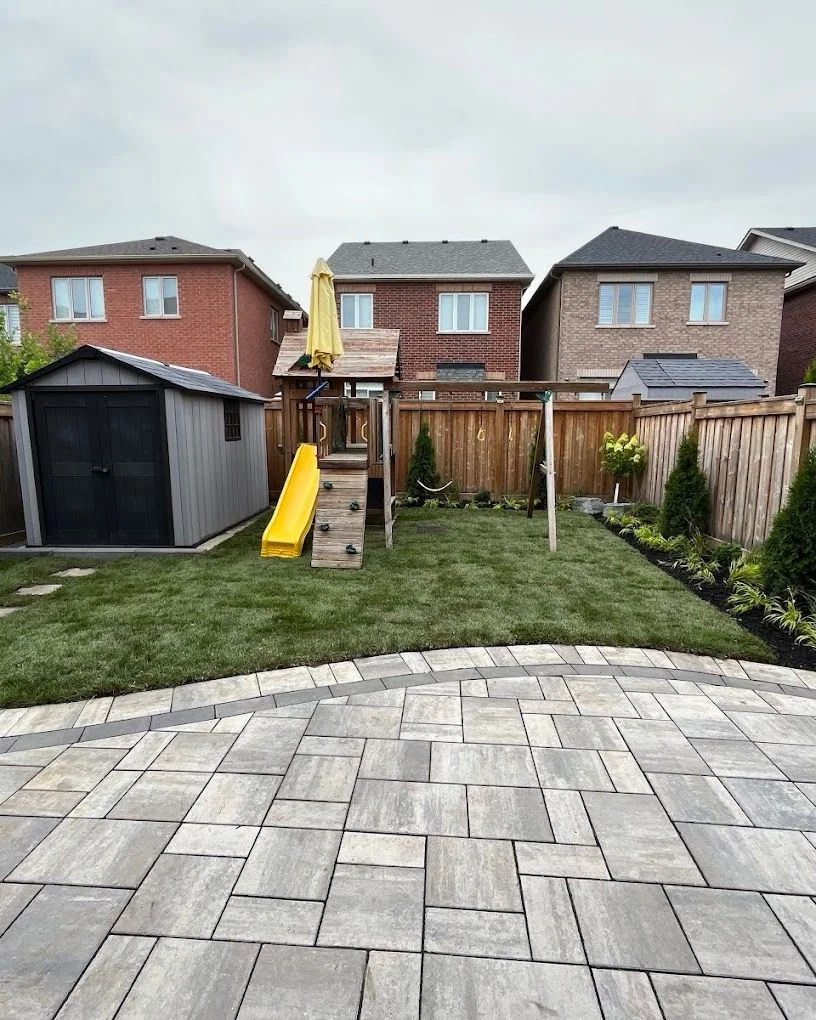 Curved paver patio overlooking a newly sodded family backyard