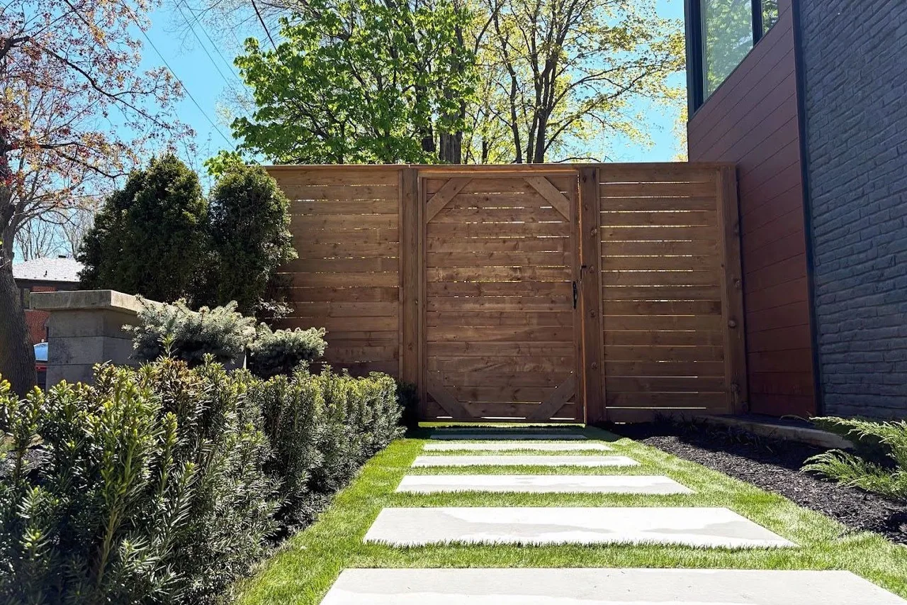 Large-format stepping stones set through lawn toward a horizontal cedar gate