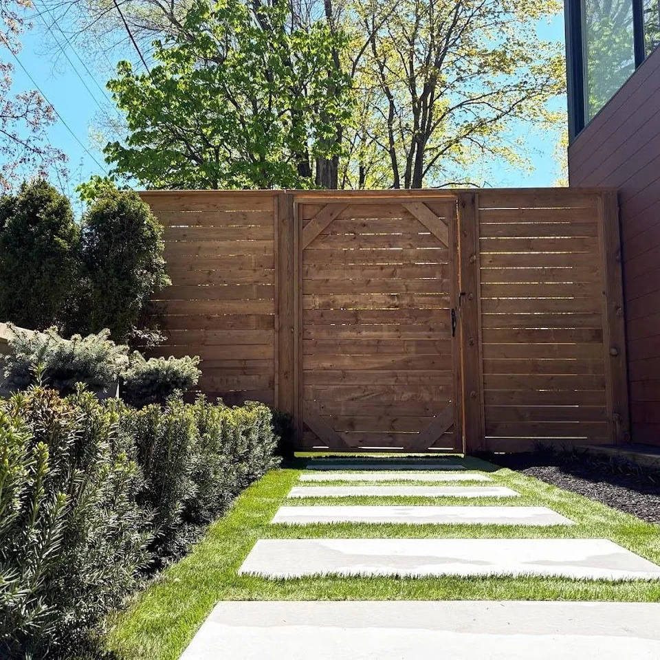 Large-format stepping stones set through lawn toward a horizontal cedar gate