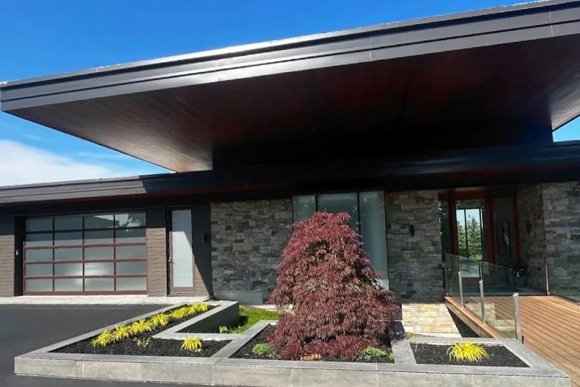 Modern home entrance framed by geometric planters and a specimen tree