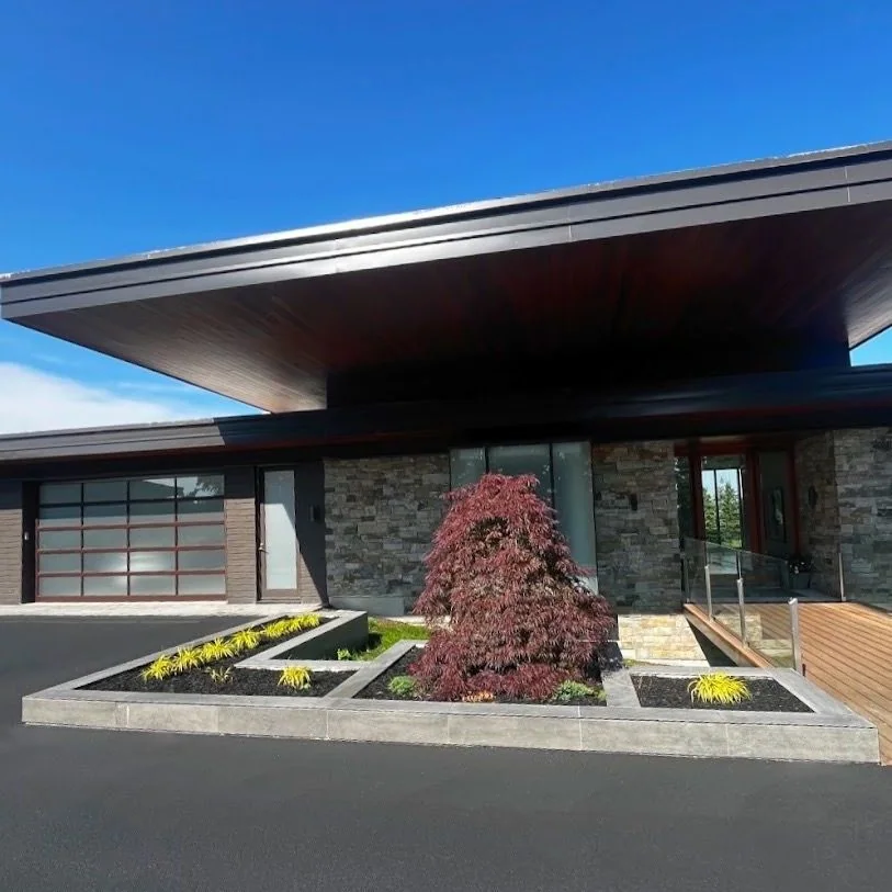Modern home entrance framed by geometric planters and a specimen tree
